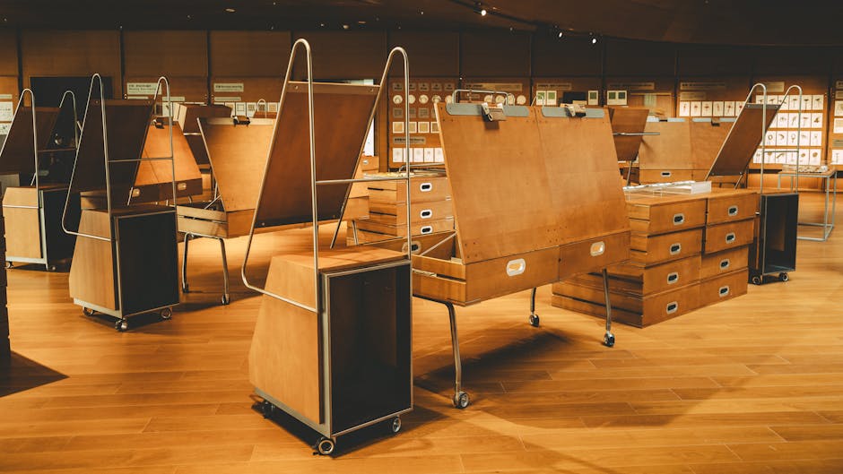 Interior view of a modern art gallery with wooden exhibition stands and artwork displays.